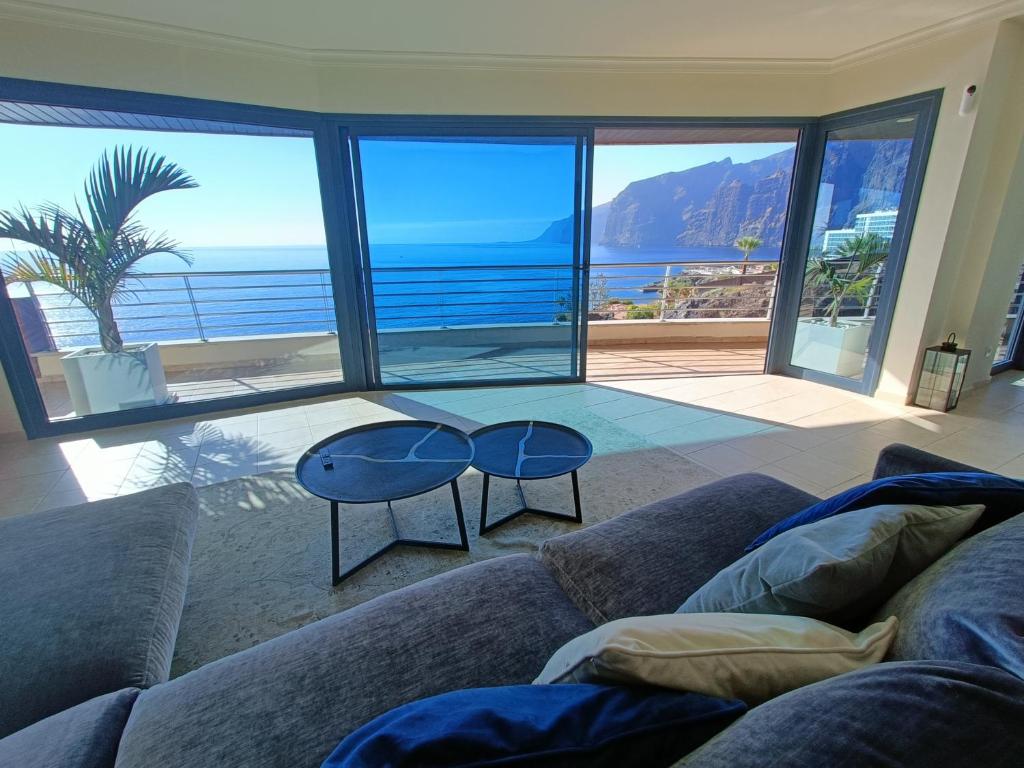 een woonkamer met een bank en uitzicht op de oceaan bij Luxury Los Gigantes Apartment in Puerto de Santiago