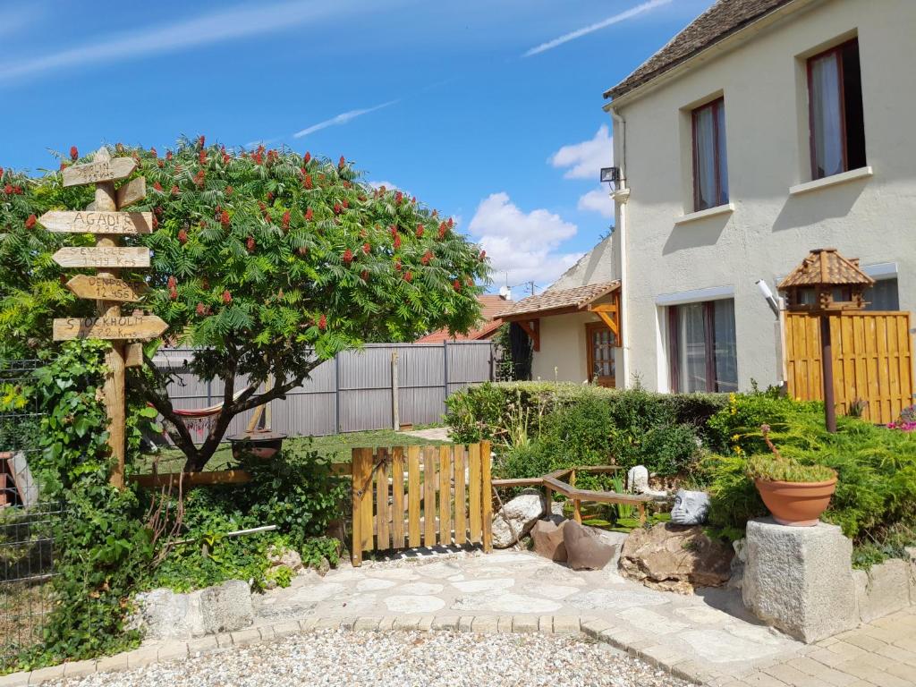 einen Garten mit einem Holzschild vor einem Haus in der Unterkunft Ferme de Beaulieu, appartement avec jardin privatif in Neauphlette