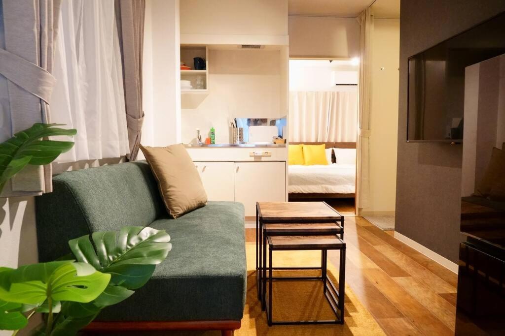 a living room with a green couch and a kitchen at Liaison Court Universal Gateway - Free Parking in Osaka
