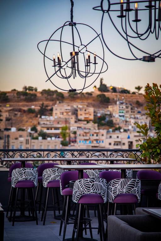 a bar with purple chairs and a view of a city at Hotel Philosophy in Amman