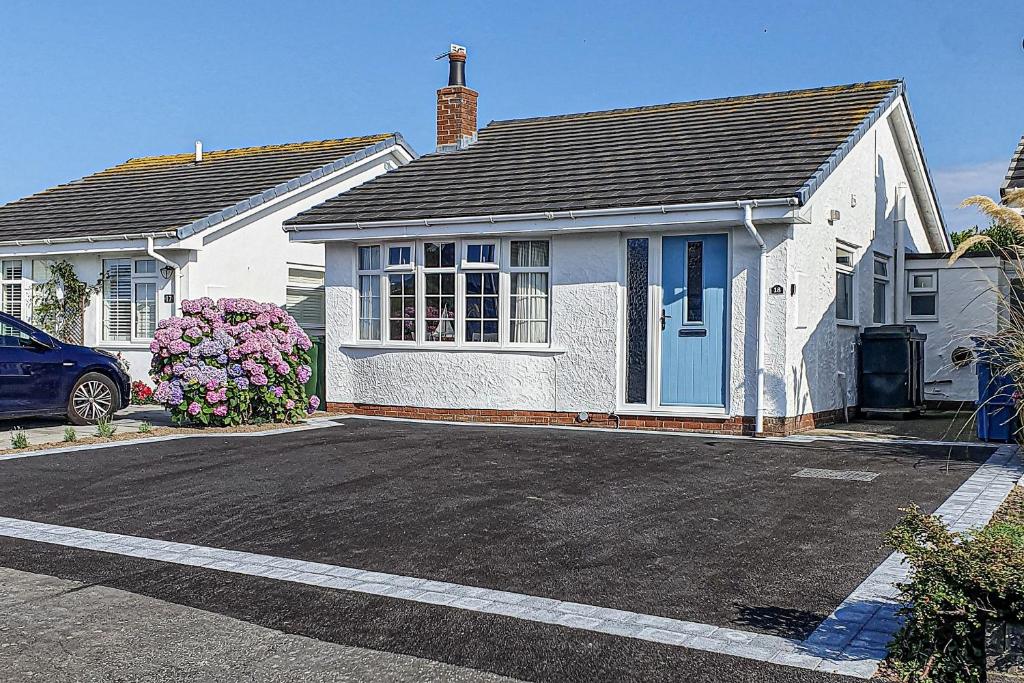 a white house with a blue door in a driveway at Tan Y Wylan in Rhosneigr