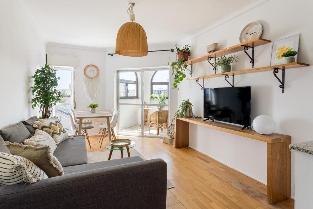 a living room with a couch and a tv at ALTIDO Bright bohemian flat in Cascais in Cascais