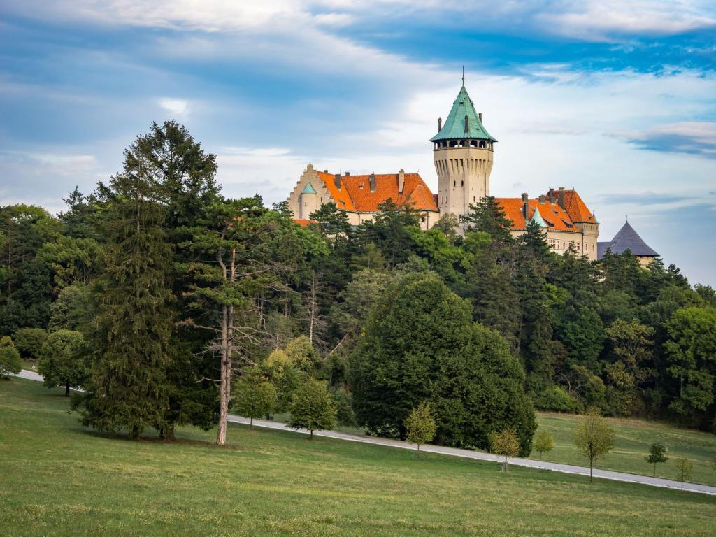 een kasteel bovenop een heuvel met bomen bij Smolenický zámok in Smolenice