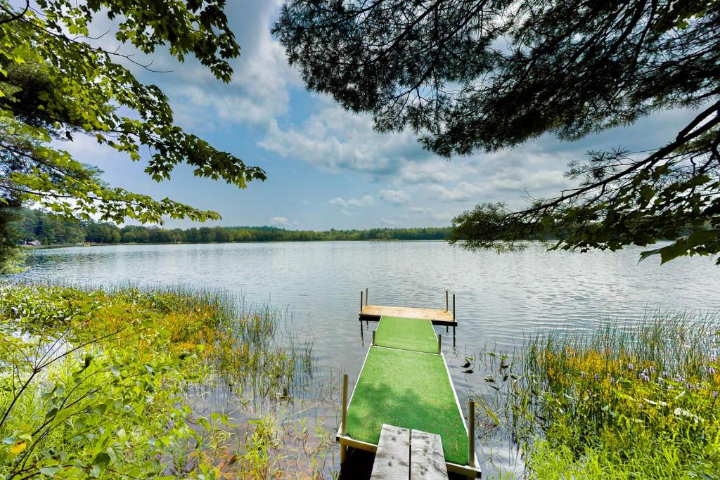 a green boat on a lake with a dock at The Lazy Lumberjack Cottages in Franklin