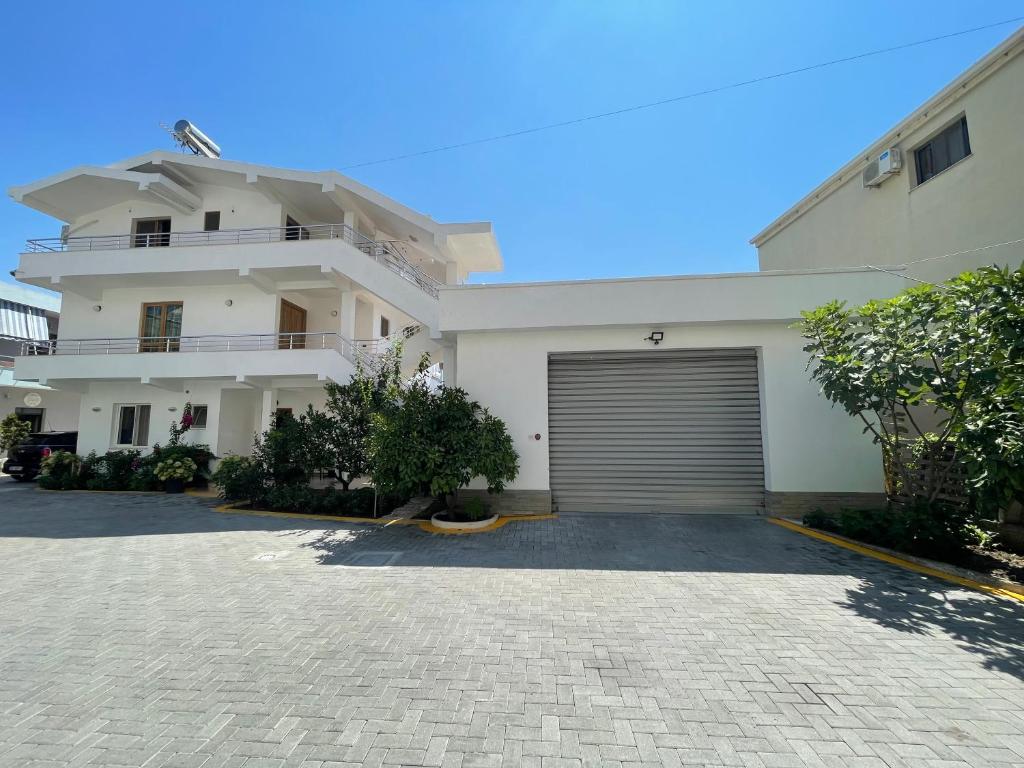 a large white house with a garage at Guest House Lionel in Durrës