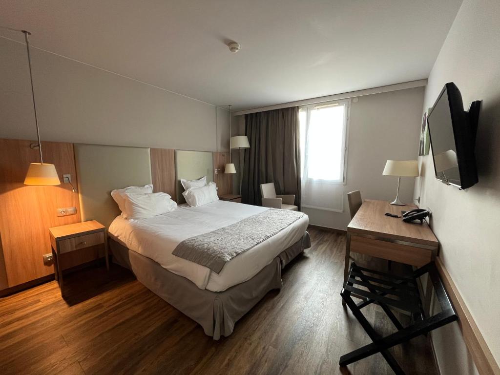 a hotel room with a bed and a desk at City Résidence Paris CDG Airport in Roissy-en-France