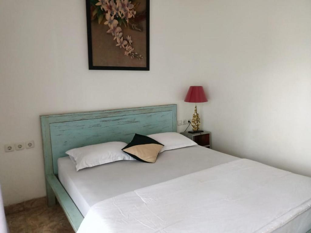 uma cama com duas almofadas num quarto em RedDoorz at Griya Cemara Homestay Yogyakarta em Yogyakarta