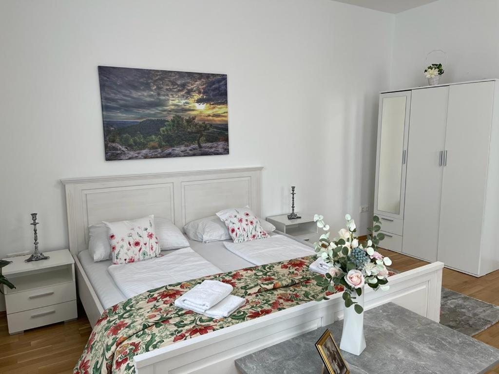 ウィーンにあるvienna city apartment 1のベッドルーム1室(花が咲く白いベッド1台付)