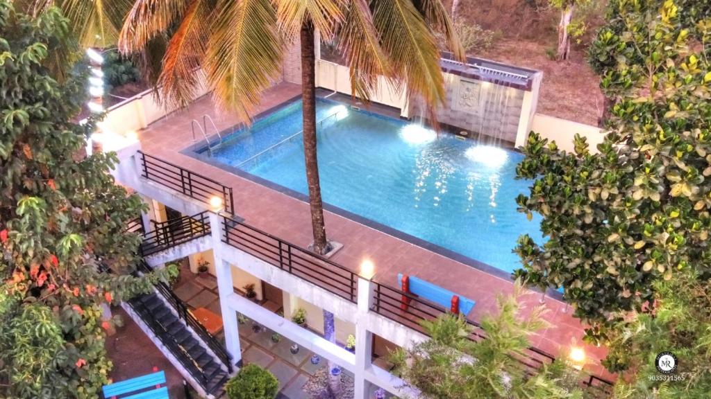 una vista aérea de una piscina con palmeras en Coorg Avani Holiday Inn, en Madikeri