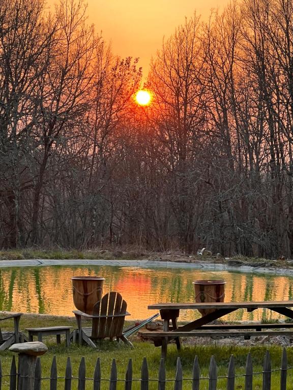 una puesta de sol sobre un estanque con una mesa de picnic y dos barriles en Domaine de Mombret Haut, en Duravel