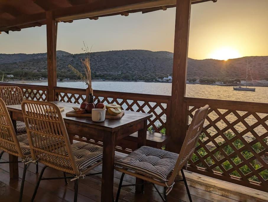 a table and chairs on a porch with a view of the water at Santa Maria - Seaside Serenity in Ierápetra