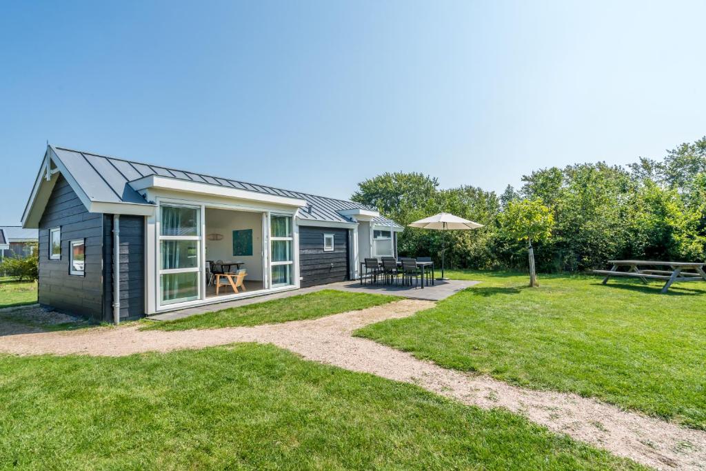 a tiny house with a patio and a yard at Duinpark Westerschouwen in Burgh Haamstede