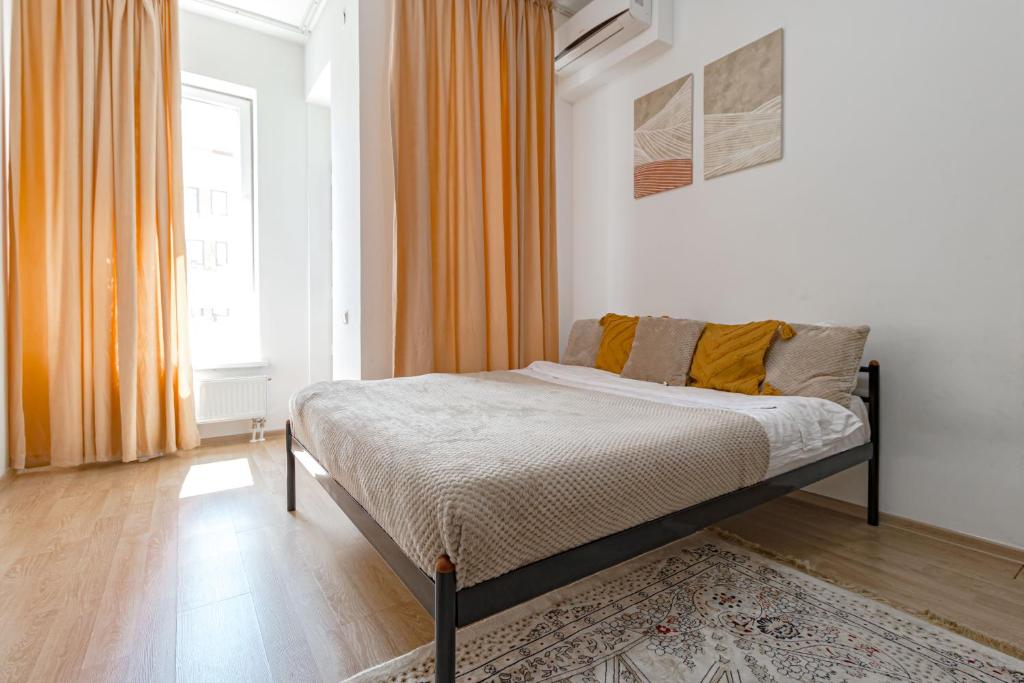 - un lit dans une chambre avec un rideau orange dans l'établissement Апартаменты в ЖК Expo Residence C, à Astana