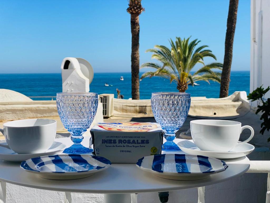 - une table avec des assiettes et des tasses et une vue sur l'océan dans l'établissement GOLDEN MILE FRONT LINE BEACH RESORT, à Marbella
