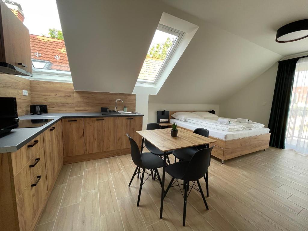 a kitchen with a table and chairs and a bed at Rezidex Apartmanház in Szeged