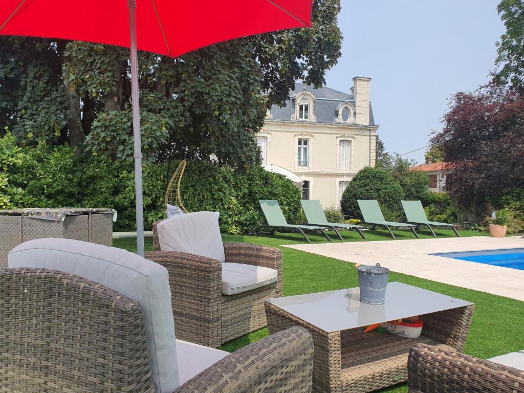 a patio with chairs and a table with a red umbrella at LES 5 ESCALES in Parthenay