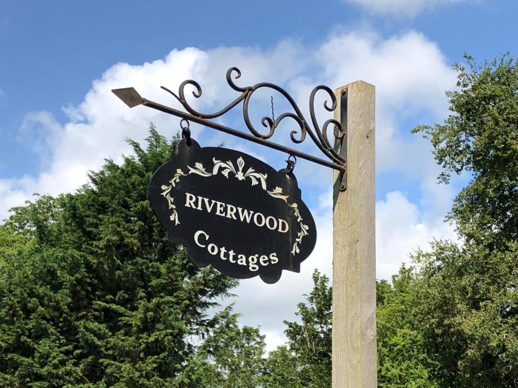 a sign on a wooden pole in front of trees at The Dairy-Petting Farm-Indoor Pool-Play Areas-Parkland-Woodland-Lake,Ponds&Stream-min2 night stay in Lechlade