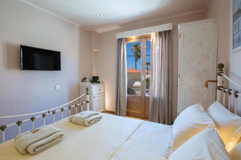 a bedroom with a bed with a television and a window at BELLA VITA boutique hotel lefkada in Lefkada