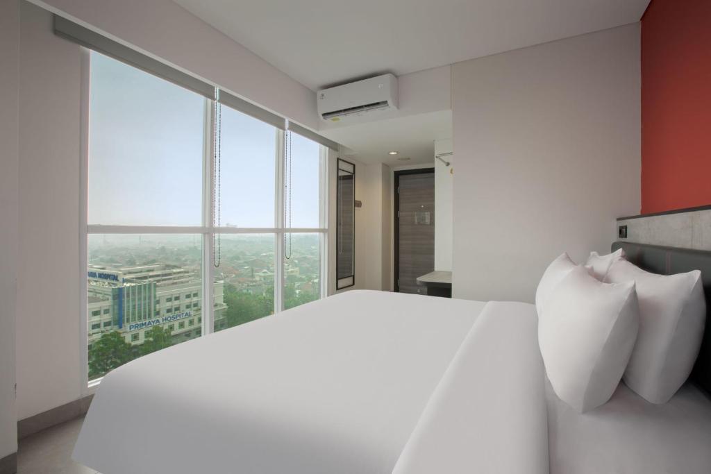 Amaris Hotel Kalimalang في جاكرتا: غرفة نوم بسرير أبيض مع نافذة كبيرة