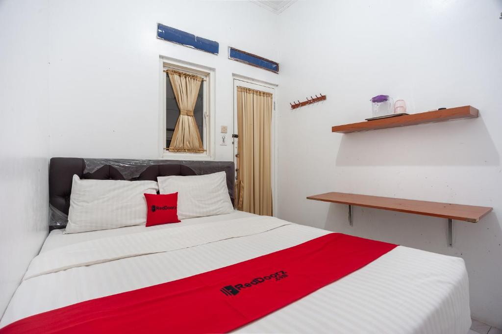 RedDoorz Syariah near PGC Cililitan في جاكرتا: غرفة نوم مع سرير مع بطانية حمراء عليه