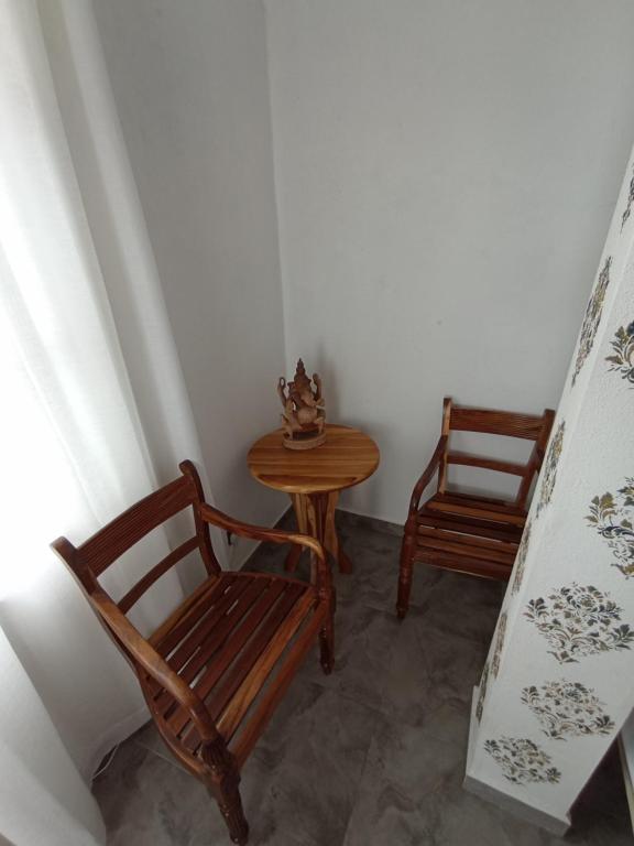 Habitación con 2 sillas de madera y mesa. en Villa Music of the ocean, en Wadduwa
