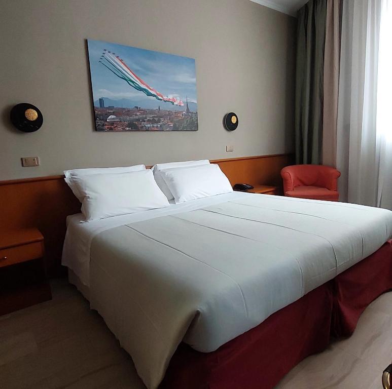 a bedroom with a large white bed with a red chair at Eurohotel in Nichelino