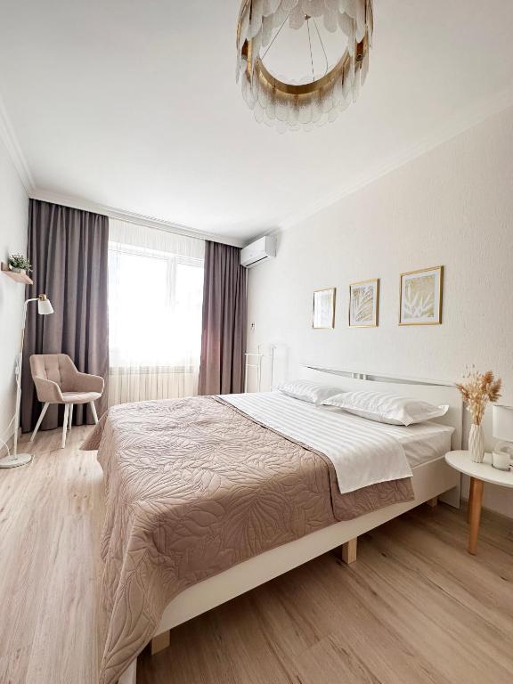 a white bedroom with a large bed and a chandelier at ЖК "Light House", 1 in Astana