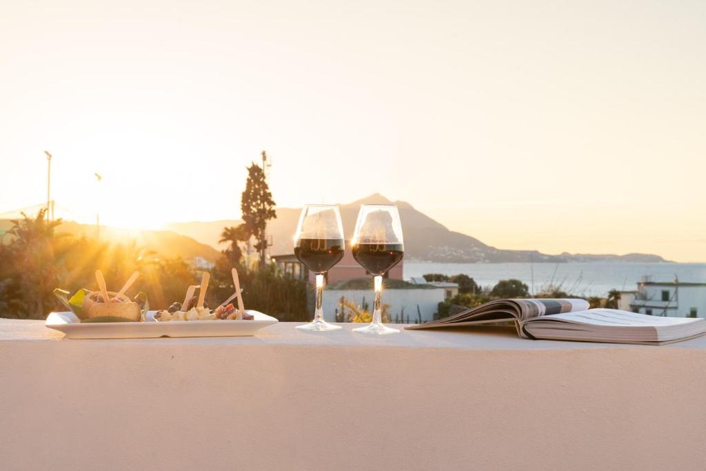 een tafel met twee glazen wijn en een boek bij la torre boutique rooms in Procida