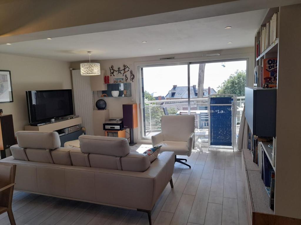 ein Wohnzimmer mit einem Sofa, Stühlen und einem TV in der Unterkunft Carpe Diem in Le Val-André