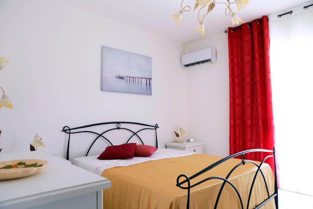 um quarto com uma cama e uma cortina vermelha em A Casa di Doralucia - Comfort a Santa Maria di Leuca em Leuca