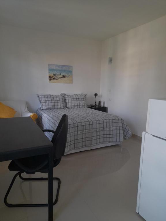 a bedroom with a bed and a desk and a refrigerator at Studio bem localizado. in Curitiba