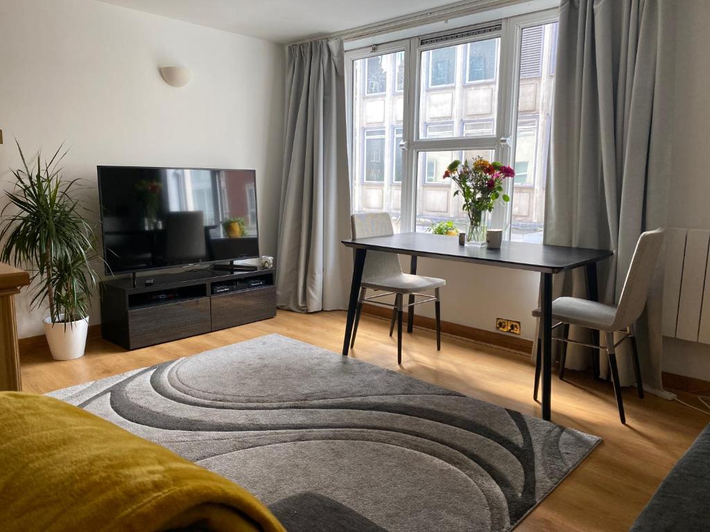 a living room with a table and a television at Prime Location Apartment - Heart of London in London