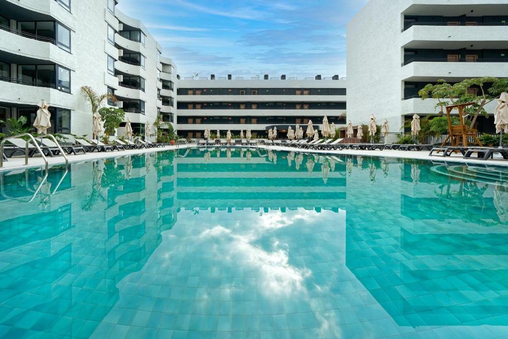 a large swimming pool with chairs and a building at HOVIMA Suites Costa Adeje in Adeje
