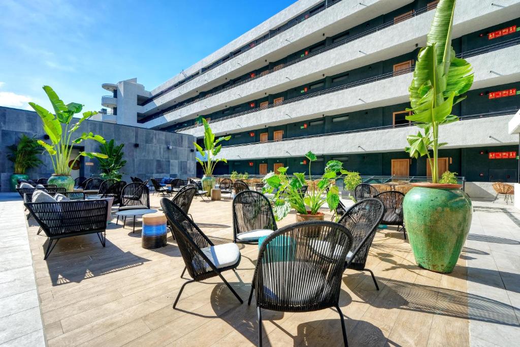 a group of chairs sitting on a patio with a building at HOVIMA Suites Costa Adeje in Adeje