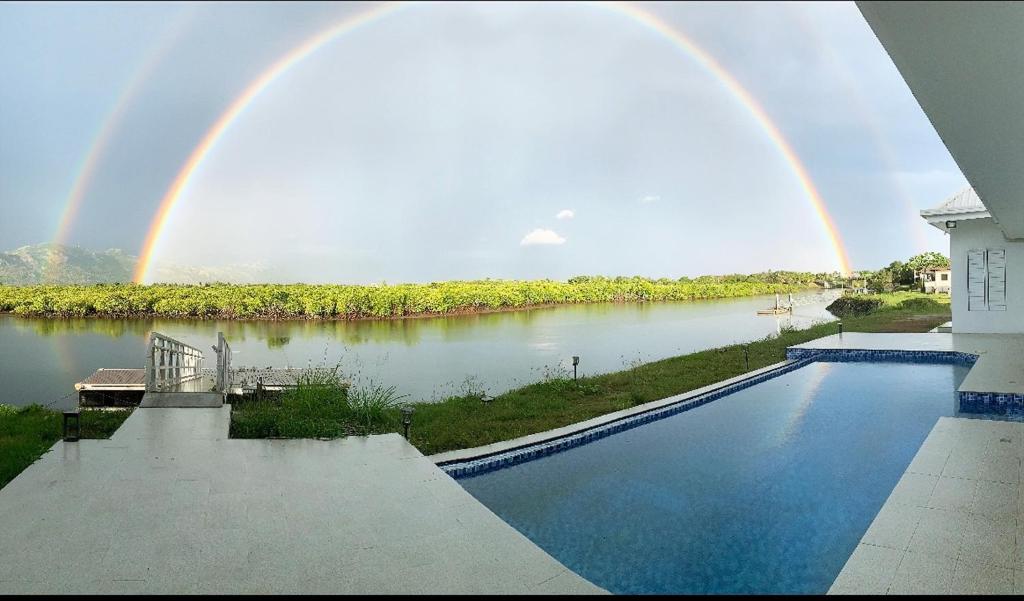 a rainbow over a river with a swimming pool at Lake Side Villa in Nadi