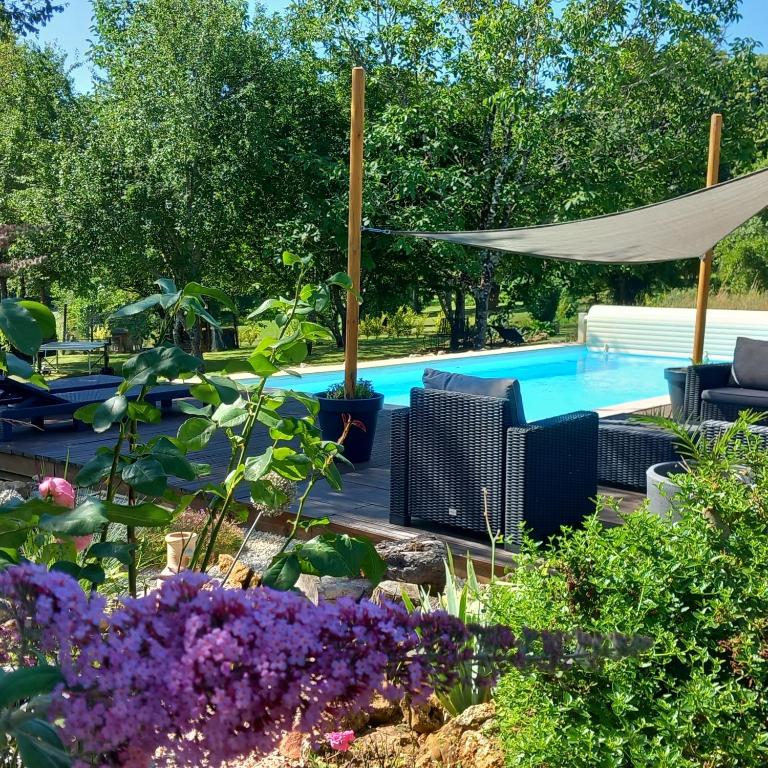 une piscine dans un jardin avec des fleurs violettes dans l'établissement LPC Dordogne Holidays - Le Petit Coin, à Lussas-et-Nontronneau