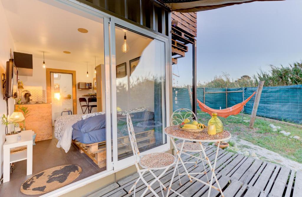 a patio with a table and a hammock on a deck at Shanti Farm Meco in Sesimbra