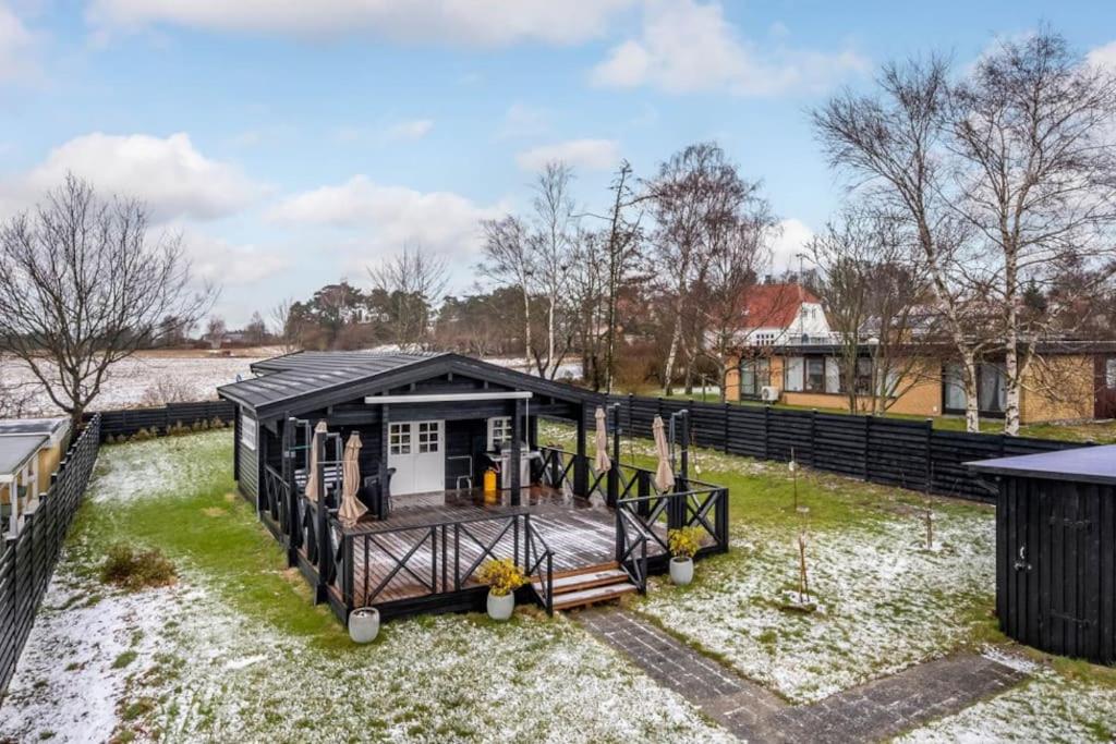 a black tiny house sitting on top of a yard at Feriehus - Ramløse, Danmark in Helsinge