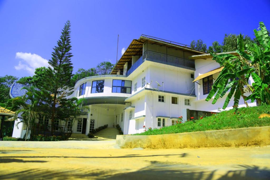 a white house with a palm tree in front of it at Mothers Bounty by Lazo , Coorg in Madikeri