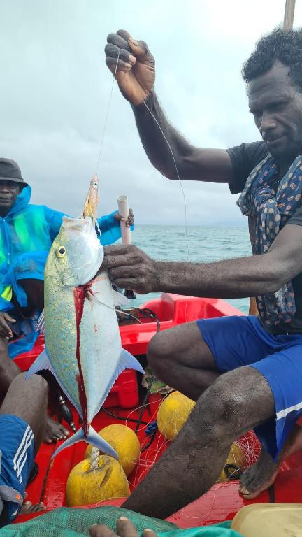 a man holding a fish on a raft at Takapuna Homestay in Gizo