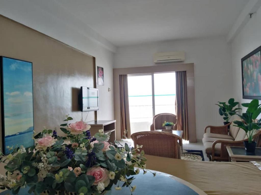 a living room with a table with flowers on it at Beachfront Sea View Penang in Tanjung Bungah