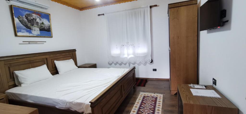 een slaapkamer met een bed, een televisie en een raam bij Hazmurat Hotel in Gjirokastër