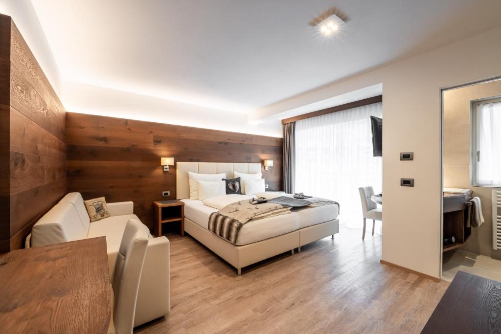 a bedroom with a bed and a desk and a table at Arya Alpine Lodge in Selva di Val Gardena