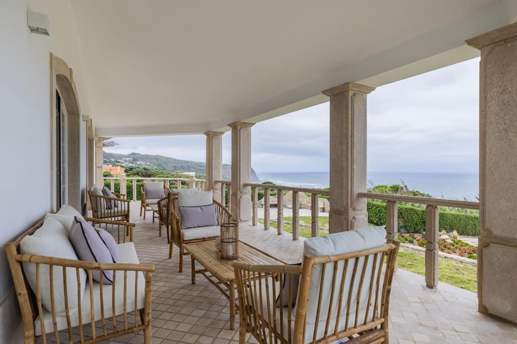 a porch with chairs and a table and views of the ocean at Windmill Beachfront Villa in Colares
