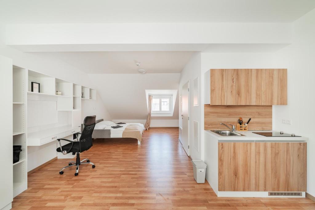 a kitchen and living room with a desk and a bed at Central City Suits in Wiener Neustadt