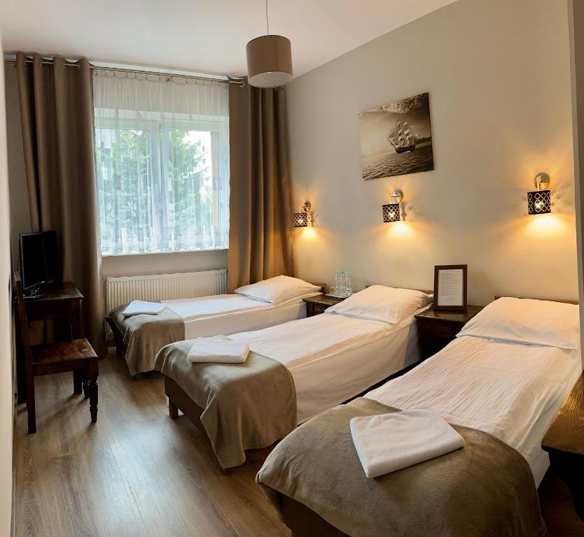 a room with three beds and a window at Hotelik Korona in Raszyn