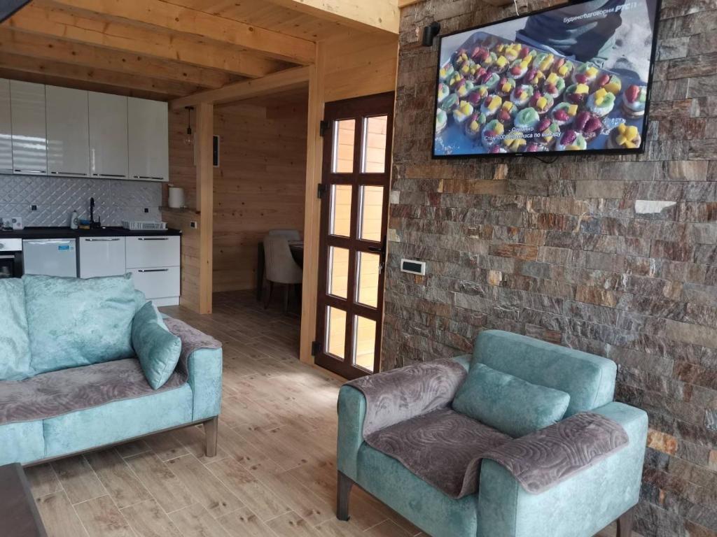 a living room with two chairs and a tv on a brick wall at Brvnare Libero TARA in Sekulić 