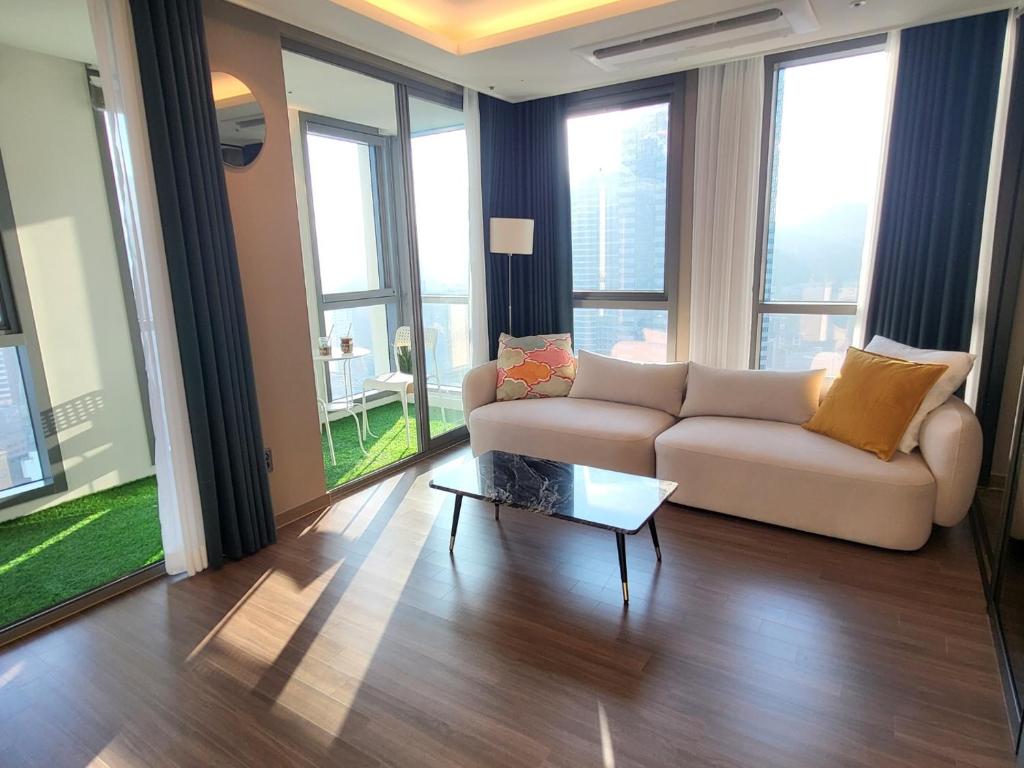 ein Wohnzimmer mit einem Sofa und einem Tisch in der Unterkunft ELBON the stay Haeundae beach in Busan