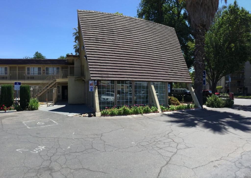 a building with a roof on top of a parking lot at Discovery Inn in Modesto
