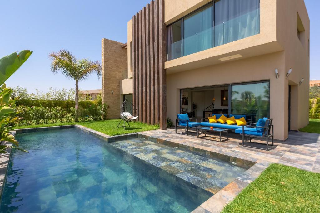 a villa with a swimming pool and a house at Villa Nounja Golf Amelkis Marrakech in Marrakech